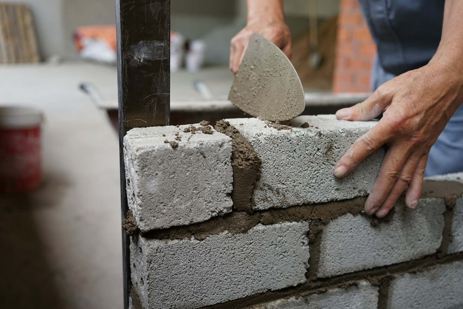 Manos levantando una pared de bloques con la paleta