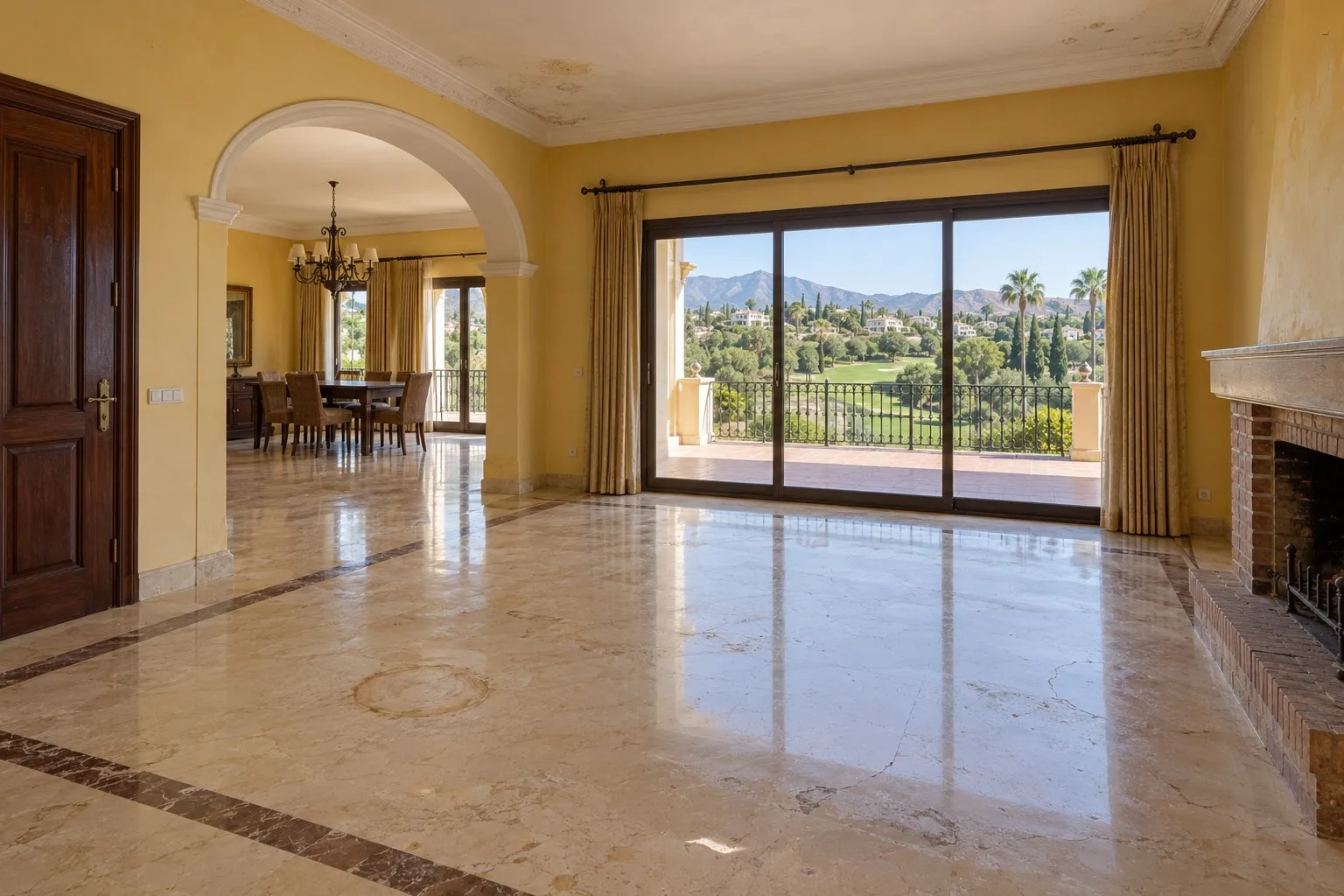 Salón de villa en Nueva Andalucía, Marbella, con suelo de mármol crema y paredes amarillas antes de la reforma