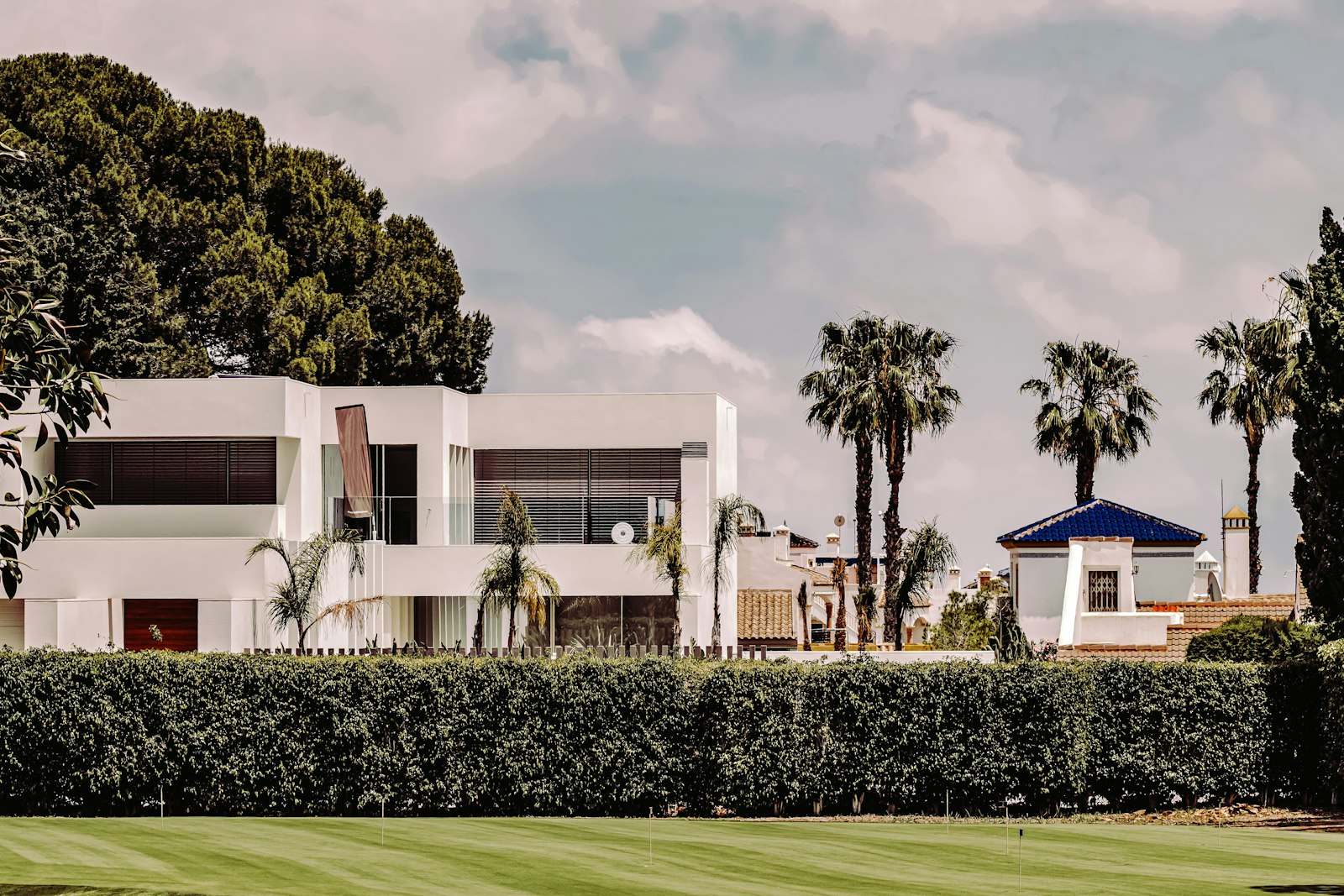 Villa blanca de estilo mediterráneo con palmeras y jardín